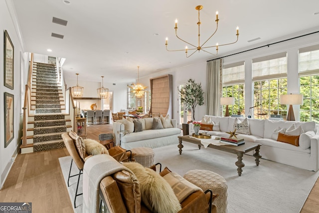 living area featuring stairway, light wood finished floors, and a chandelier