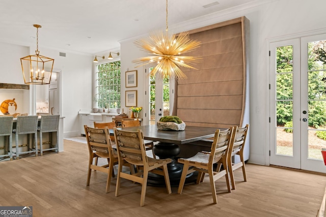 dining space with visible vents, a notable chandelier, french doors, light wood-style floors, and crown molding