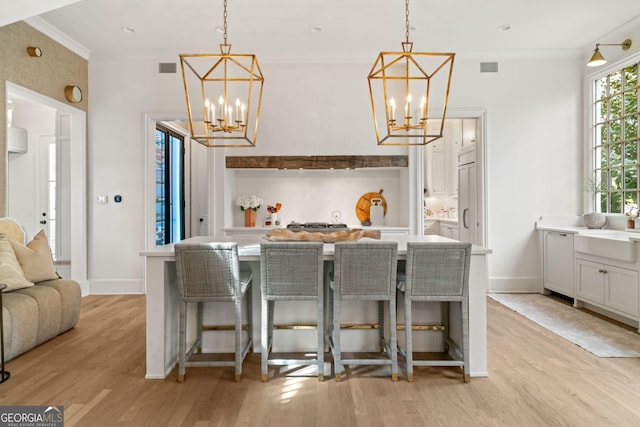 kitchen with a notable chandelier, light wood-style floors, and ornamental molding