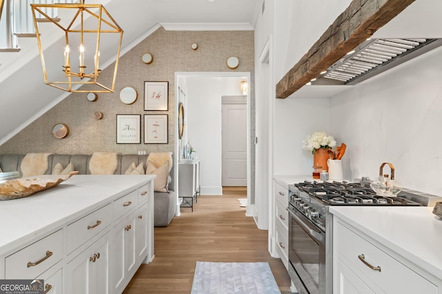 kitchen featuring lofted ceiling, light countertops, white cabinets, light wood-style floors, and high end stainless steel range