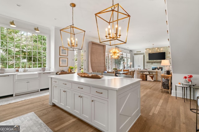 kitchen featuring a sink, light wood-style floors, a chandelier, and a center island