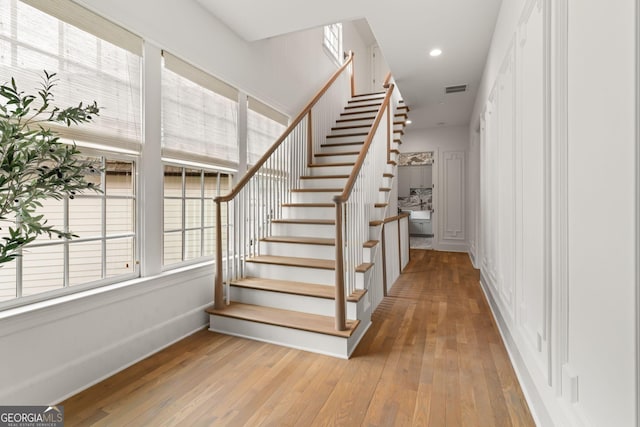 stairway featuring recessed lighting, visible vents, wood-type flooring, and plenty of natural light