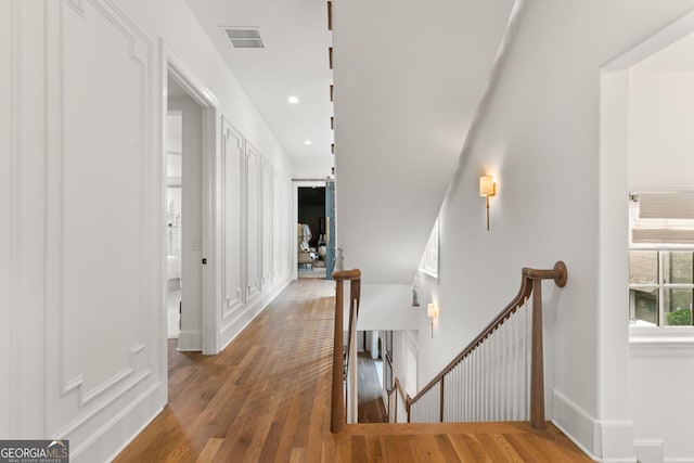 corridor with an upstairs landing, visible vents, recessed lighting, and hardwood / wood-style floors