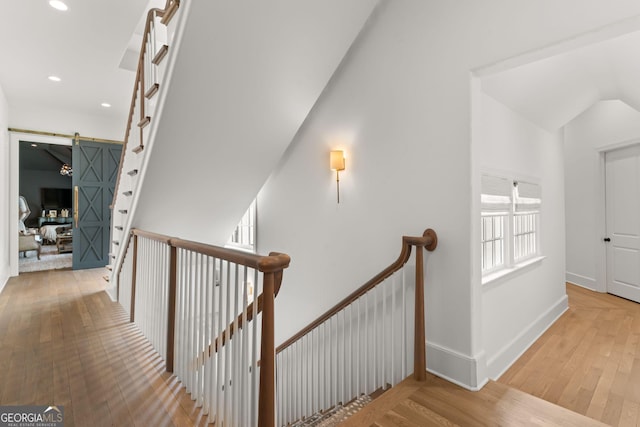 stairs with recessed lighting, baseboards, a barn door, and wood-type flooring