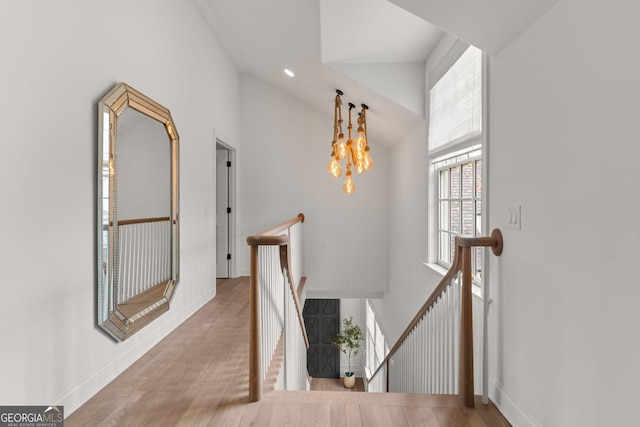 hallway featuring an upstairs landing, baseboards, lofted ceiling, and wood finished floors