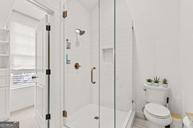 bathroom with toilet, baseboards, and a stall shower