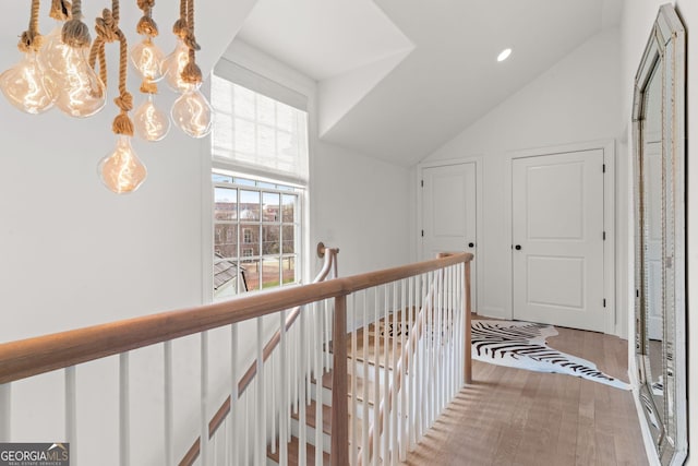 corridor featuring an upstairs landing, vaulted ceiling, and wood finished floors