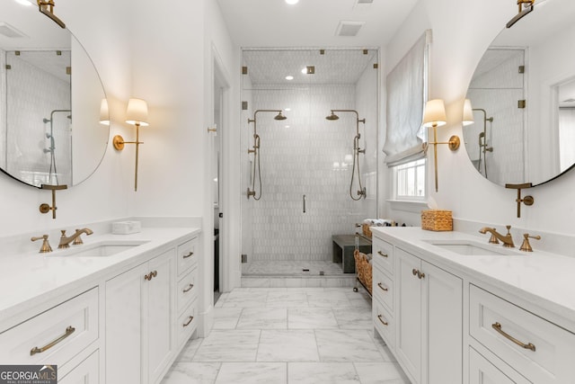 bathroom with marble finish floor, a stall shower, two vanities, and a sink