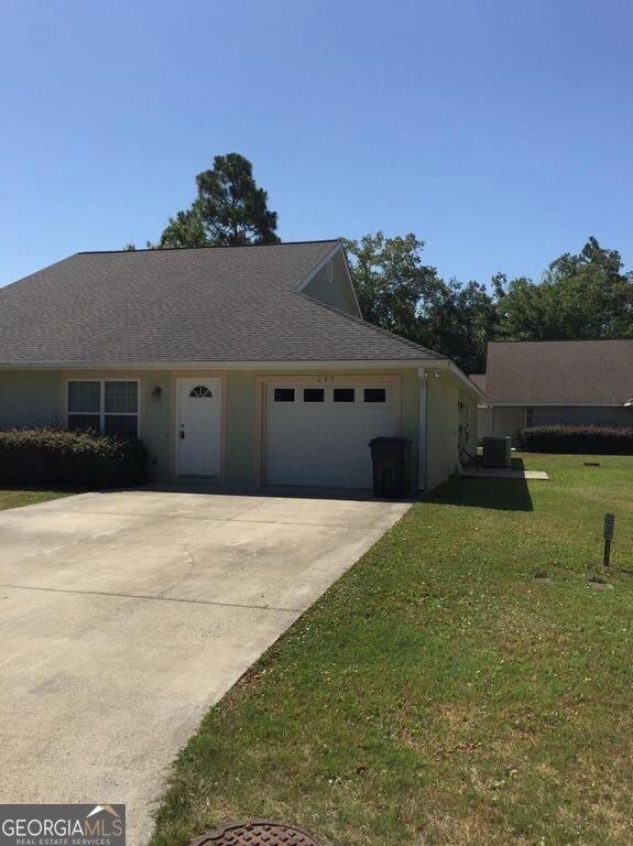 view of front of property featuring a shingled roof, a front yard, central AC unit, a garage, and driveway