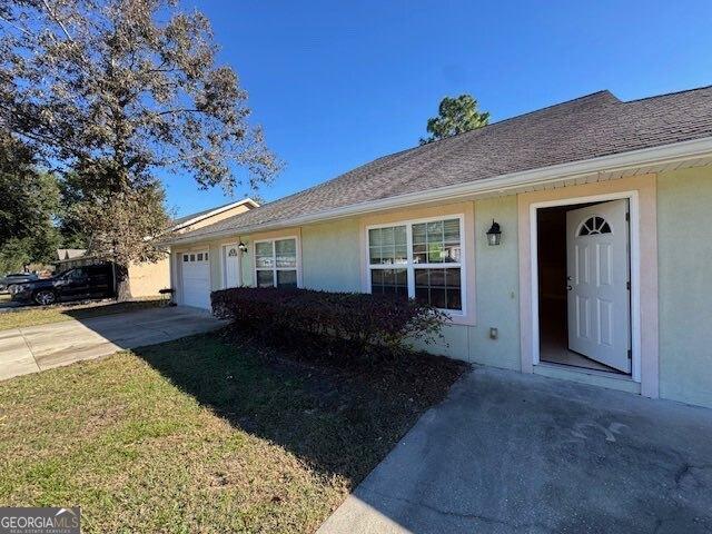 single story home with an attached garage, driveway, and stucco siding