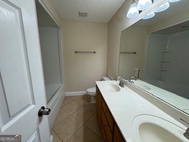 full bath featuring tile patterned floors, a textured ceiling, a shower, and a sink