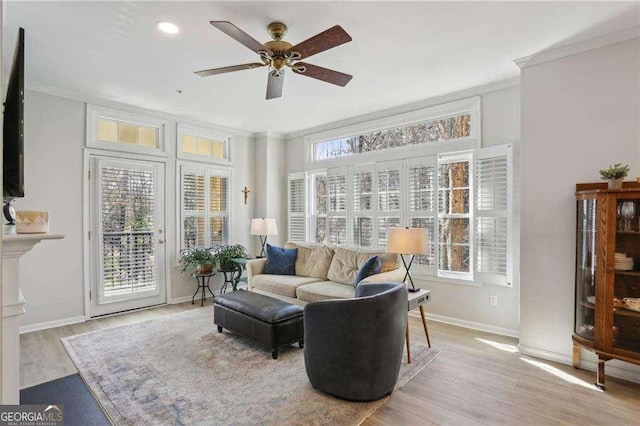 living area featuring baseboards, a ceiling fan, wood finished floors, and crown molding