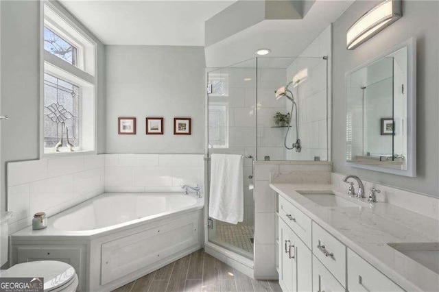 full bathroom featuring a bath, a shower stall, double vanity, and a sink