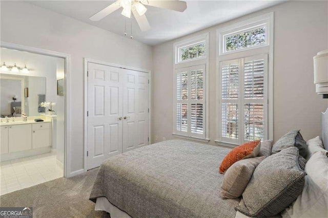 bedroom with a sink, connected bathroom, light tile patterned floors, light colored carpet, and ceiling fan