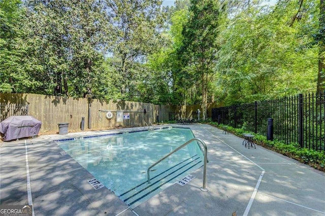 community pool featuring grilling area, fence private yard, and a patio