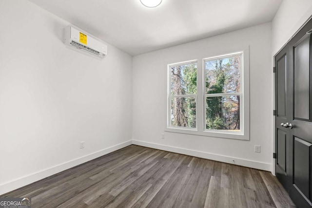 interior space with dark wood-style floors, baseboards, and a wall unit AC