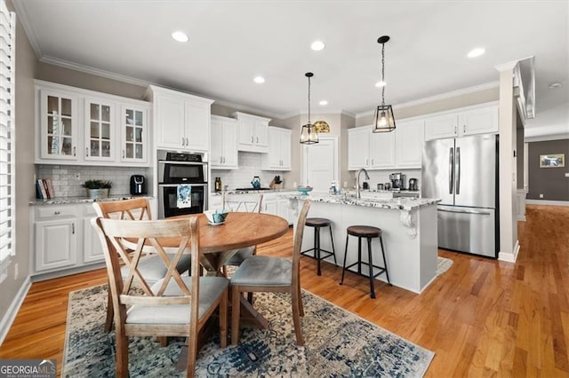 dining space featuring light wood finished floors, recessed lighting, crown molding, and baseboards