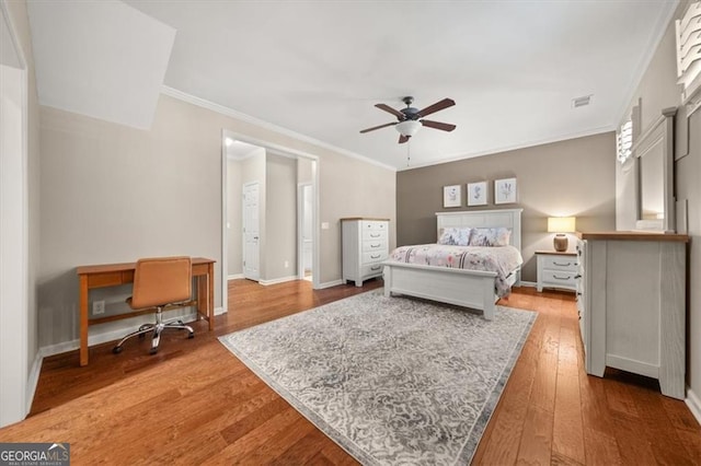 bedroom featuring hardwood / wood-style floors, baseboards, visible vents, and ornamental molding