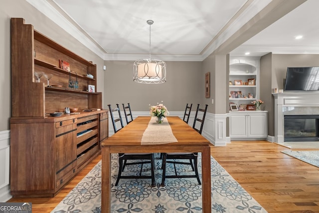 dining area featuring built in features, crown molding, and light wood-style floors