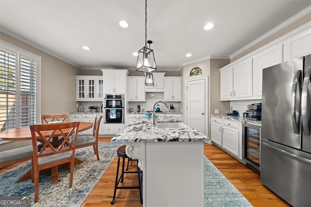 kitchen featuring beverage cooler, stainless steel appliances, crown molding, and a sink