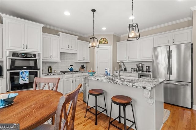 kitchen featuring stainless steel appliances, white cabinets, and light wood-style flooring