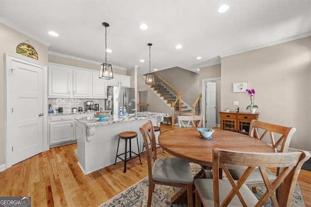 dining area featuring recessed lighting, light wood-style flooring, and stairs