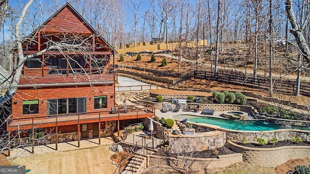 back of property featuring an in ground hot tub, fence, an outdoor pool, and a patio