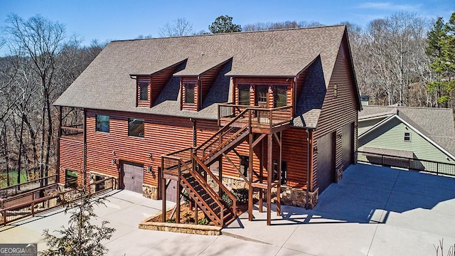 view of front of property with a shingled roof, stairway, concrete driveway, a garage, and stone siding