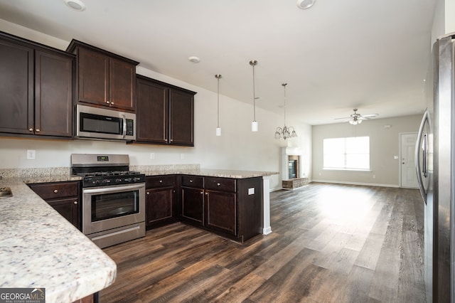 kitchen with a ceiling fan, open floor plan, a peninsula, appliances with stainless steel finishes, and dark brown cabinets