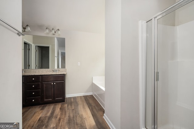 bathroom with vanity, wood finished floors, baseboards, a shower stall, and a garden tub