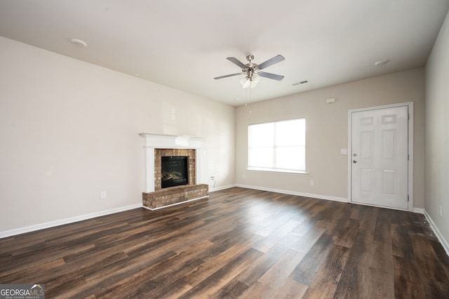 unfurnished living room with visible vents, a ceiling fan, dark wood-style floors, baseboards, and a brick fireplace