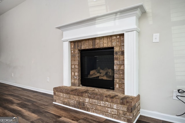 interior details with baseboards, a brick fireplace, and wood finished floors