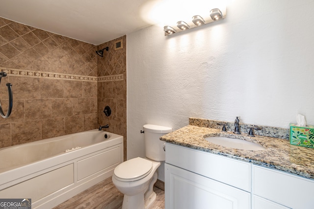 full bath featuring toilet, shower / tub combination, wood finished floors, a textured wall, and vanity