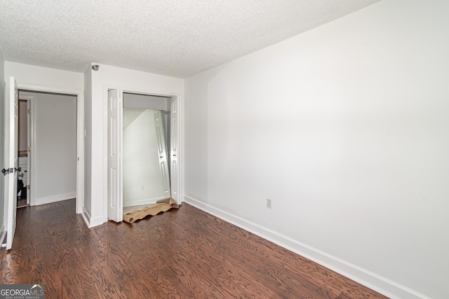 unfurnished bedroom featuring dark wood-type flooring, baseboards, a closet, and a textured ceiling