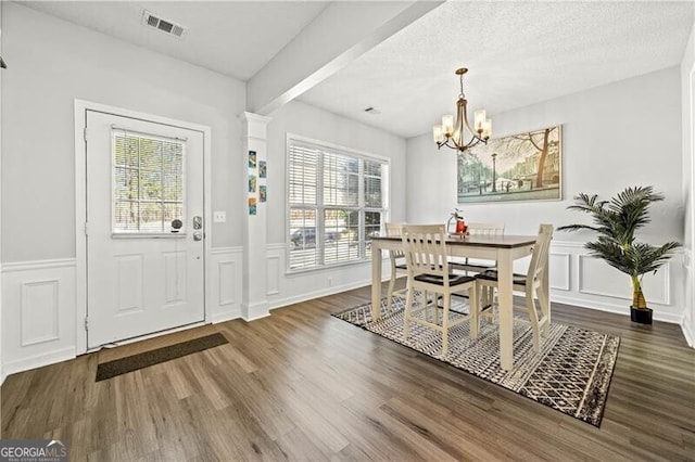 dining space with a wealth of natural light, a textured ceiling, wood finished floors, and a decorative wall