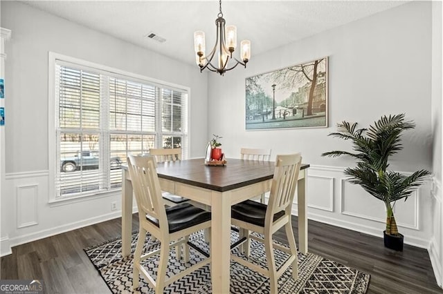 dining space featuring a chandelier, visible vents, a wainscoted wall, and wood finished floors