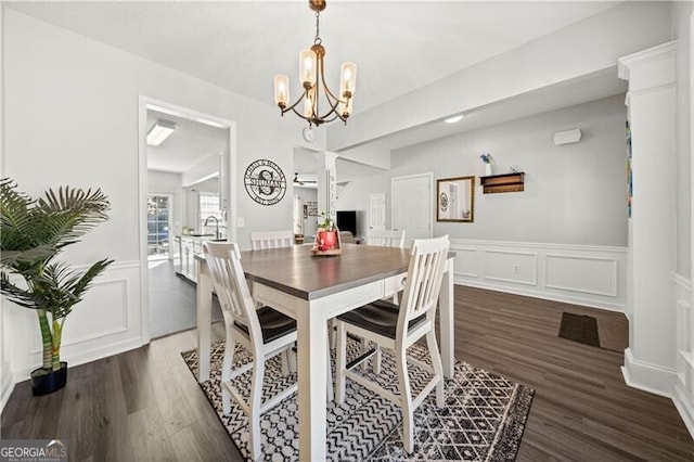 dining room with a wainscoted wall, a notable chandelier, wood finished floors, and a decorative wall