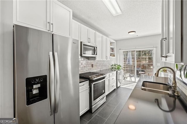 kitchen with decorative backsplash, white cabinets, appliances with stainless steel finishes, and a sink