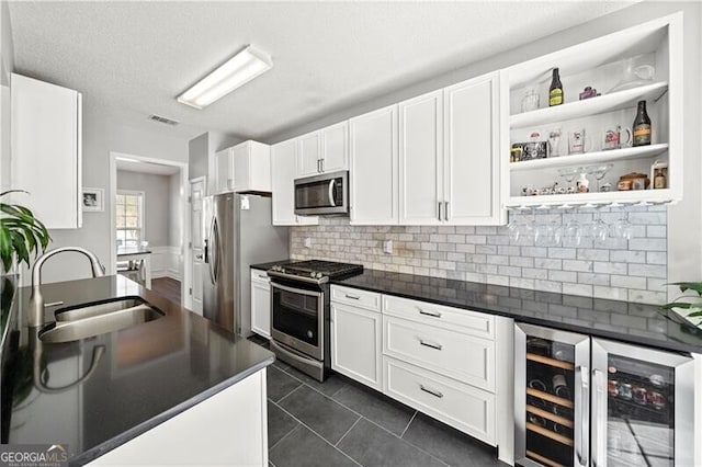 kitchen featuring a sink, stainless steel appliances, dark countertops, and white cabinets