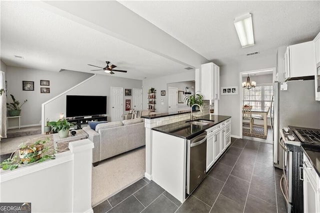 kitchen with a sink, stainless steel appliances, dark countertops, and white cabinets