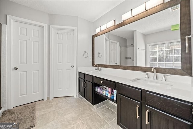 bathroom with a sink, a shower, and double vanity