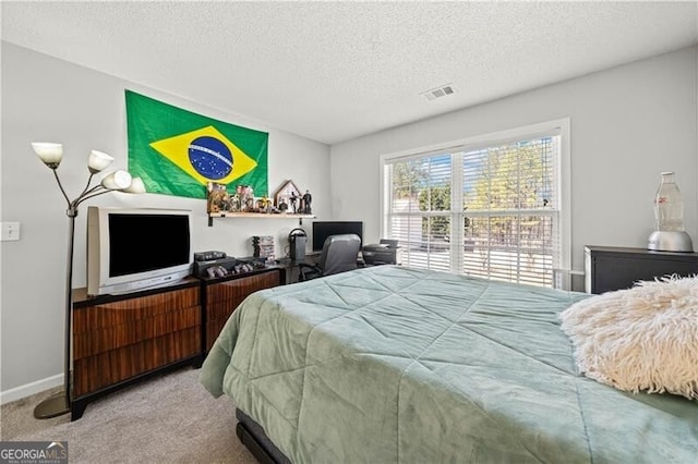 carpeted bedroom with visible vents, a textured ceiling, and baseboards