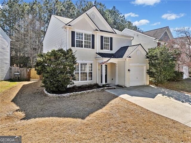 traditional-style home with concrete driveway, fence, a garage, and stucco siding