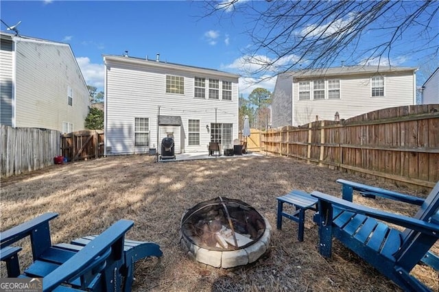 rear view of house featuring a patio, a fenced backyard, and an outdoor fire pit