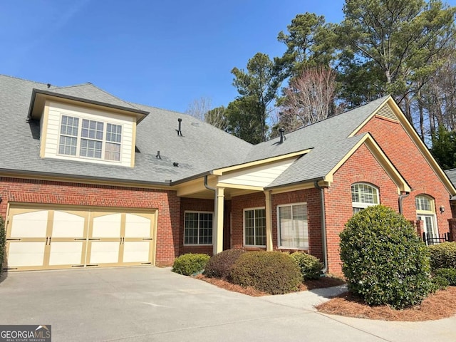 view of front of house with brick siding, driveway, and a shingled roof