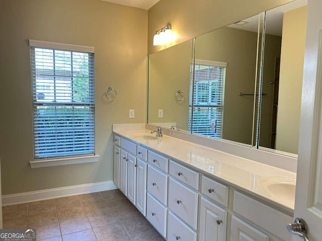 bathroom featuring tile patterned flooring, double vanity, baseboards, and a sink