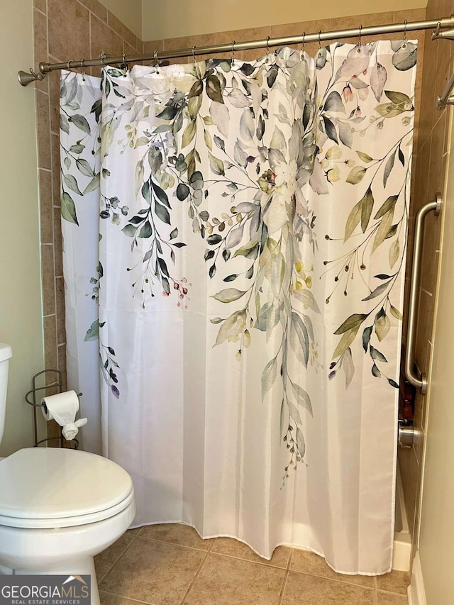 full bath featuring curtained shower, toilet, and tile patterned flooring