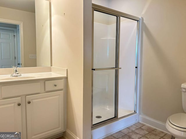 bathroom with vanity, toilet, baseboards, and a stall shower