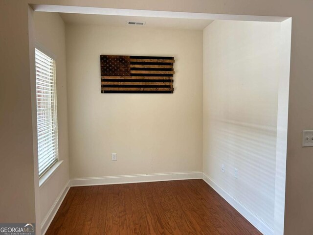 unfurnished room with dark wood finished floors, visible vents, and baseboards