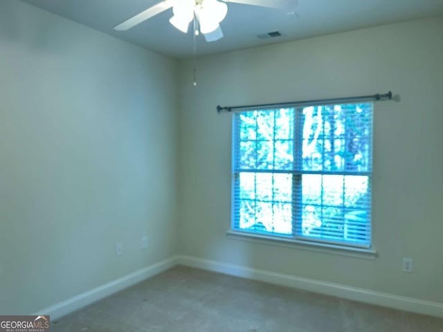 carpeted empty room featuring a ceiling fan and baseboards